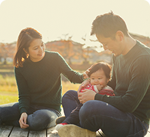 Two parents sat with their baby on a bench